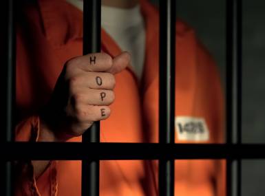 Hope word on imprisoned man fingers, holding jail bars, dream about freedom