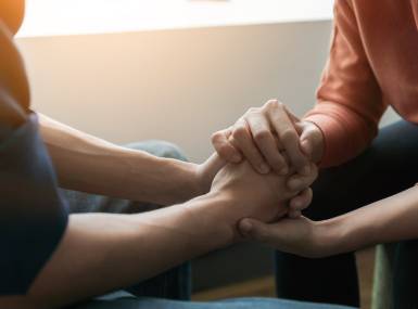 Psychologist sitting and touch hand young depressed asian man for encouragement 
