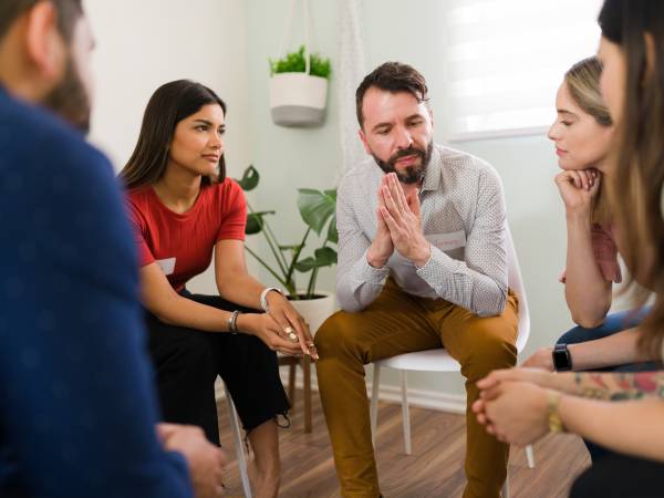 Man in his 30s asking for help at a rehab meeting