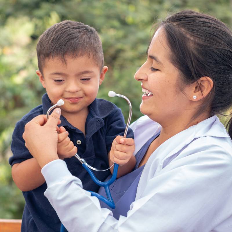Portrait of a doctor and a child with Down syndrome smiling together.